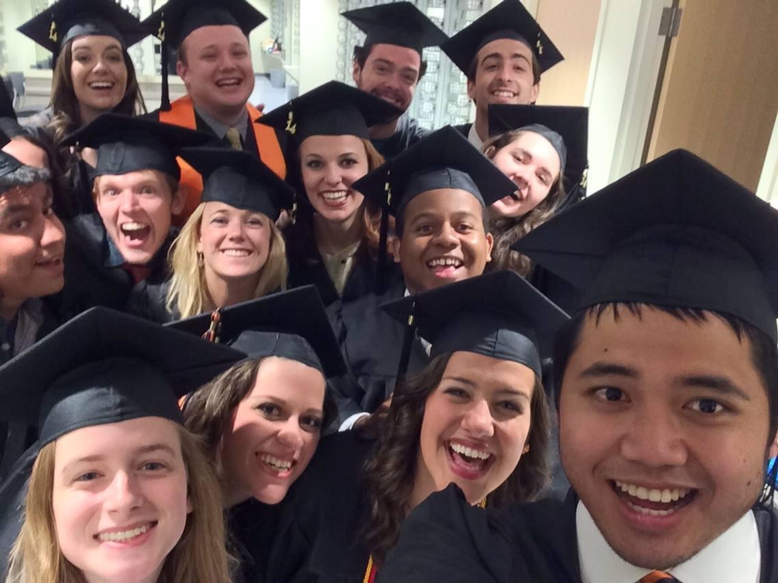 Selfie-style photo of a group of students in caps and gowns, smiling.
