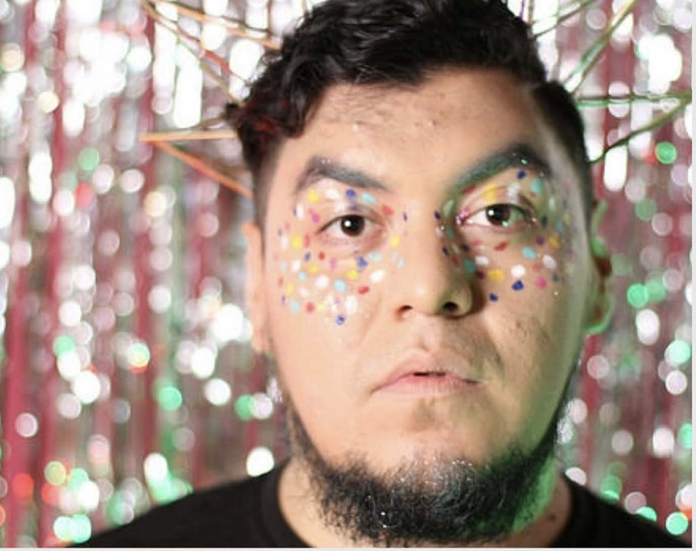 A face with beard against a shimmering, multi-color backdrop