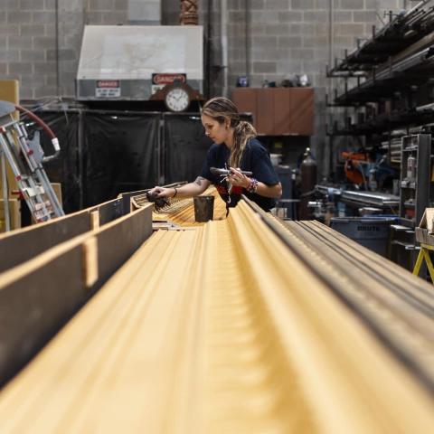 Woman woodworking, telephoto perspective down the work table.