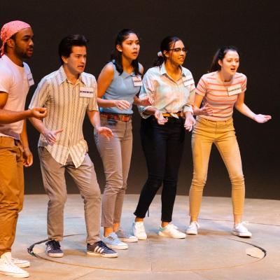 The "Somebodies," five actors, stand together facing an unseen person.