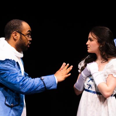 SAPPHIRE HYACINTH: An actor and actress facing each other, each with hands up as though protesting what the other is saying.