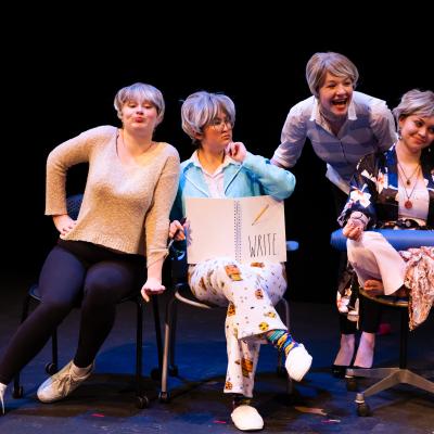 Several actors bunched together, some in chairs, some standing or leaning, all looking as though the tea has just been spilled.