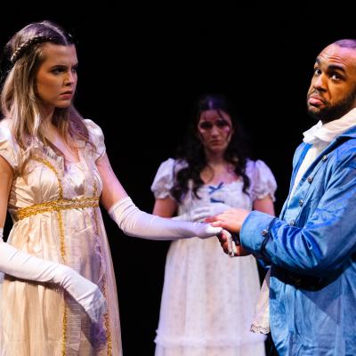 SAPPHIRE HYACINTH: An actor facing out, holding the hand of an actress who looks confused. Another actress watches from the background.