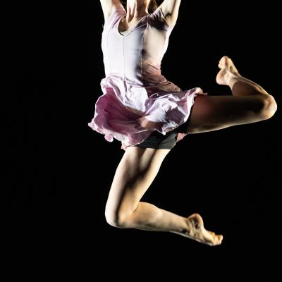 single dancer body mid-jump, legs bent, one behind and one beneath