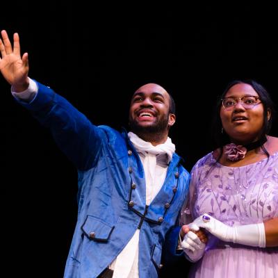 SAPPHIRE HYACINTH: Two actors looking off into the distance together, one gesturing as if describing the future or a distant place.