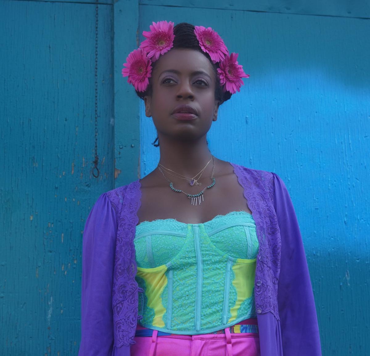 An African-American woman in colorful dress with a pink floral crown.