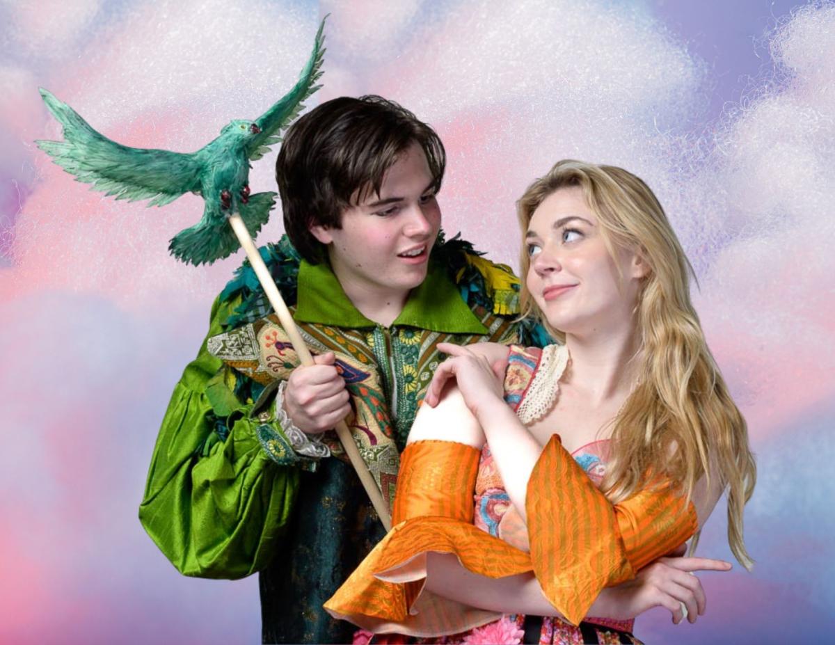Young blonde woman (right) looks at a green bird flying toward her with the help of a puppeteer.