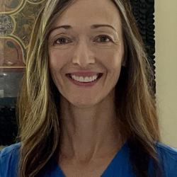 Woman facing the camera and smiling, stonework interior background