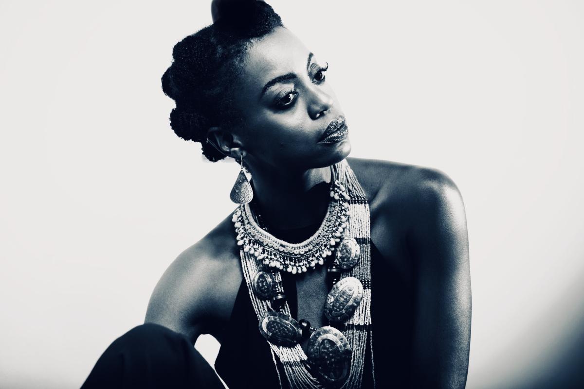 An African-American woman in a seated pose with knees raised, face in profile.